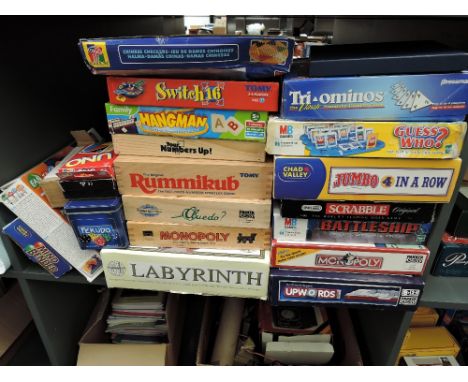 A shelf of mainly modern games including Guess Who, Monopoly, Scrabble, Rummikub, Cludo, Hangman etc