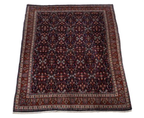 A Kashan carpet, the navy central field with a repeating herati and sylised flowerhead pattern, within a crimson border incor