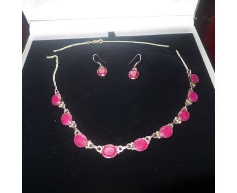 A cased sterling silver and ruby suite of jewellery consisting of a necklace and a pair of earrings