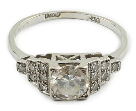 An Art Deco 18ct white gold, platinum and single stone diamond ring, with twelve stone diamond chip set stepped shoulders, th