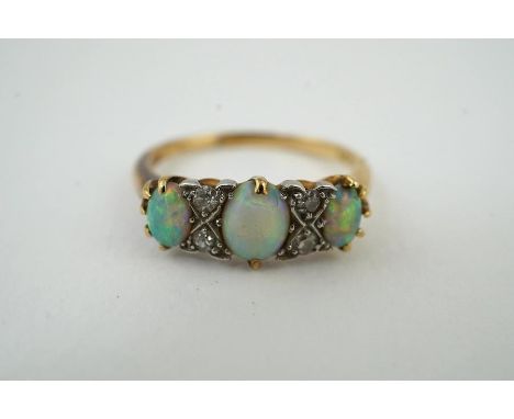 A yellow metal  (stamped 18) and three stone white opal set half hoop ring, with diamond chip spacers, size M, gross weight 3