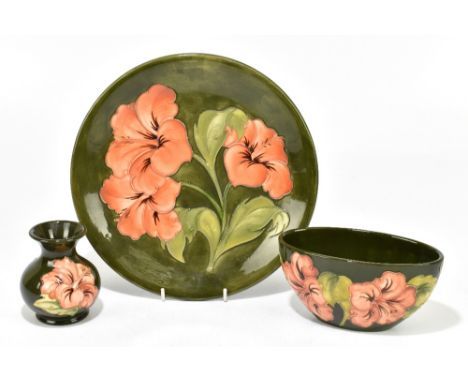 MOORCROFT; three pieces decorated in the 'Coral Hibiscus' pattern on a green ground, comprising circular plate, diameter 26cm