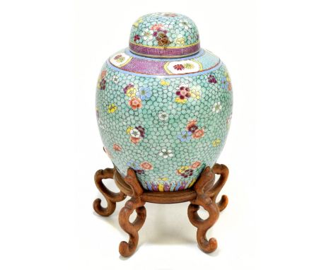 A late 19th century Chinese Famille Rose jar and cover, enamel painted with floral sprays on a mottled green ground, paper la