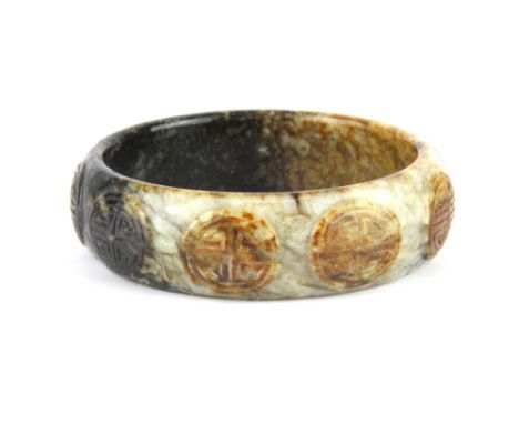 An unusual carved mixed colour jade bangle, W. 2cm, Dia. 6.5cm.