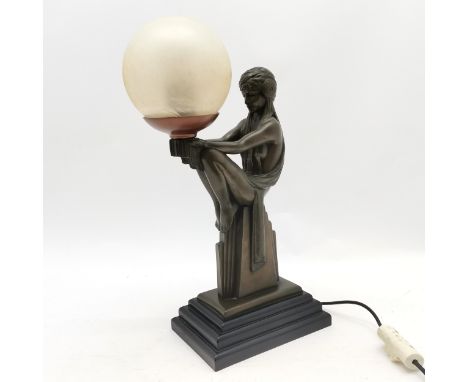 Art deco style lamp of a seated figure holding a glass globe shade  45cm high 