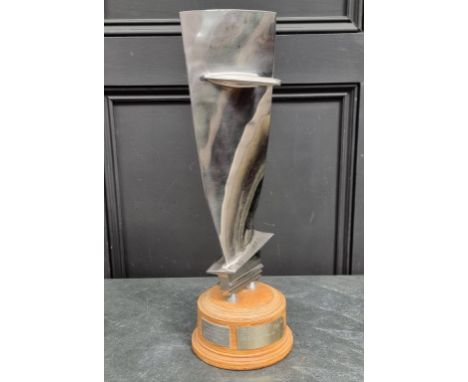 A polished aluminium trophy, on plywood socle, 52.5cm high.