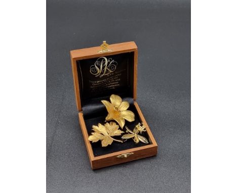 A Thai gold plated orchid brooch, 4.5cm wide, boxed; together with two other gilt floral brooches. (3)