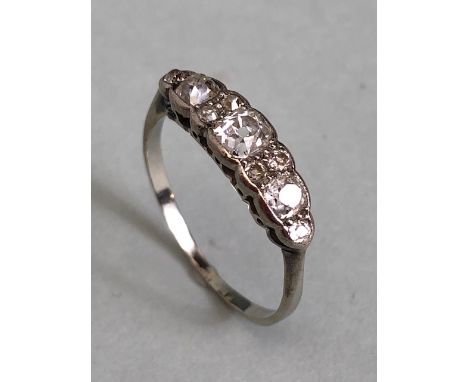 Unmarked white Gold Diamond ring set with nine diamonds, the largest central diamond flanked by a pair of diamonds then two o