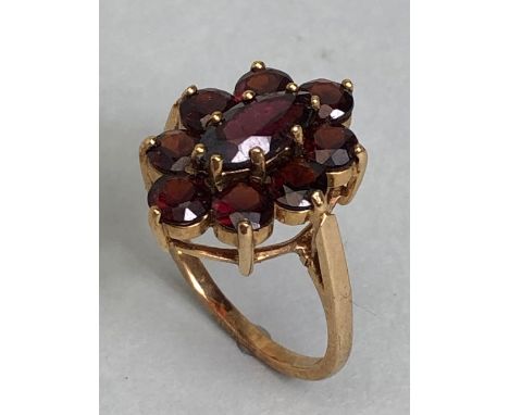 9ct gold daisy style ring set with nine garnets in claw settings with large oval central garnet on raised gold pierced platfo