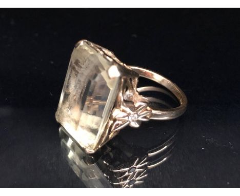 9ct yellow gold ring mounted with a pale quartz  Emerald cut stone the shoulders of butterfly design set with single white st