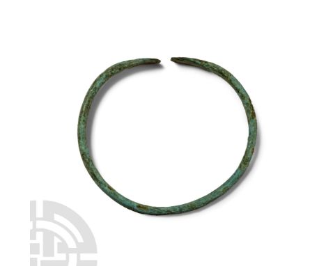 Late Bronze Age, 1st millennium B.C. Round in section with flattened trapezoidal finals, each incised with a saltire.  6.99 g