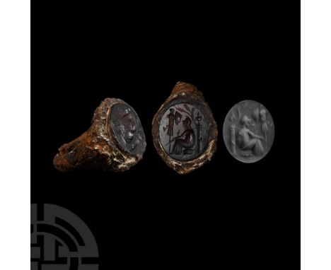 1st-4th century A.D. discoid bezel with intaglio scene of figure wearing a helmet and pleated robe sitting on a rock beneath 