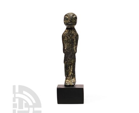 Circa 6th century B.C. Standing figure wearing a tunic with straight arms placed to the sides, with exaggerated facial featur