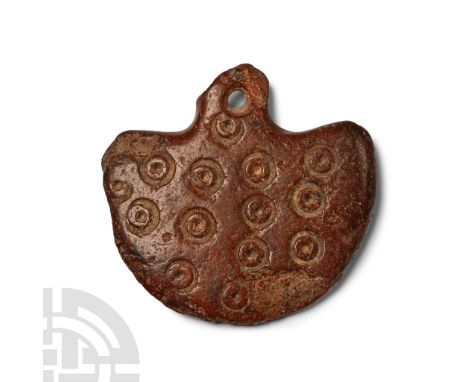 2nd millennium B.C. or later. D-shaped plaque with integral pierced suspension lug, decorated with columns of incised ring-an
