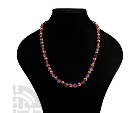 20th century A.D. Comprising alternating amethyst spherical beads and gold-coloured beads with enamel detailing.  80 grams, 6