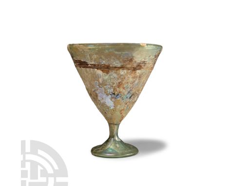 Circa 5th-6th century A.D. An aqua glass goblet with conical foot, curved body, rolled rim with applied trail below. Cf. Whit