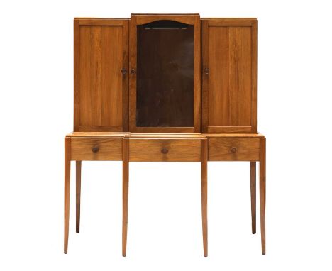 A Gordon Russell Art Deco walnut breakfront cabinet,1930s, with a central glazed door, flanked by a blind door on either side