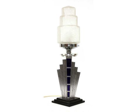 An Art Deco table lamp, with a frosted and stepped glass shade, raised on a polished steel ring over a fan-shaped stand, on a