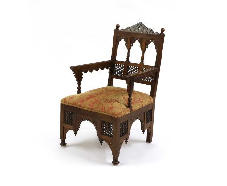 An Aesthetic Movement Moorish mahogany armchair,c.1910, in the Liberty &amp; Co. manner, the back with a pointed cornice over