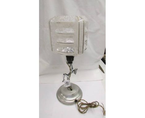 An art deco chrome nude figure table lamp with glass shade.