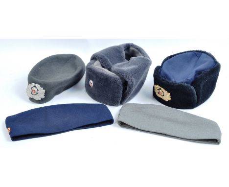 A collection of x5 assorted East German NVA National People's Army uniform hats comprising x2 winter fleece lined Ushanka sty