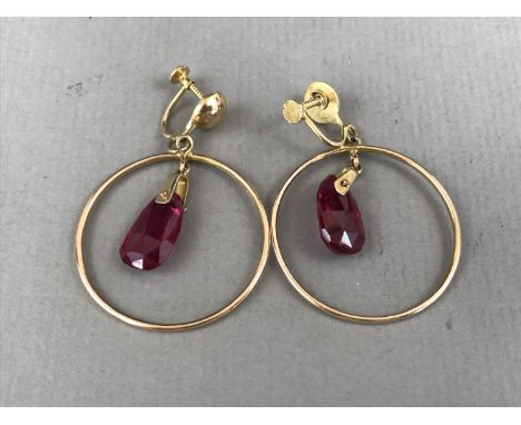 A pair of contemporary Verneuil ruby ear pendants, each having a faceted drop suspended within a high-carat yellow-metal annu