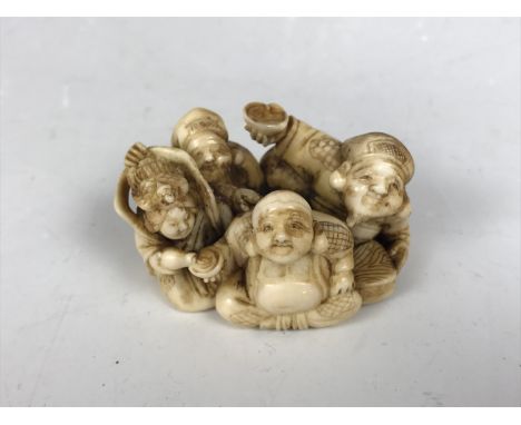A Meiji Japanese large marine ivory katabori netsuke depicting characters sat serving a Hotei-like figure, character marks to