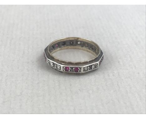 A vintage diamond and ruby eternity ring, of decagonal section, the faces alternately claw-set with pairs of stones on white 