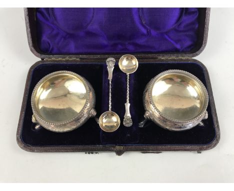 A cased pair of Victorian silver cauldron salt cellars and spoons, having punched and wriggle-work engraved decoration, surro
