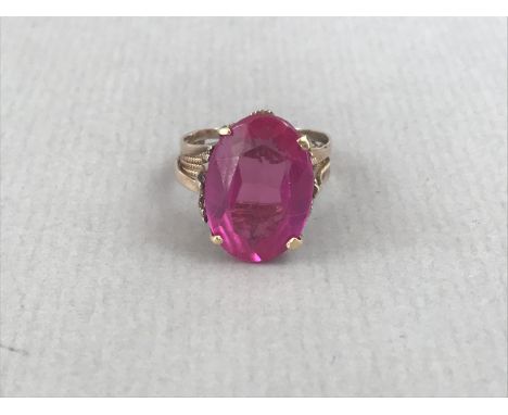 A contemporary Verneuil ruby cocktail ring, the oval-cut stone of approximately 16 x 11.5 mm, claw-set above a bifurcated yel