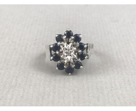 A vintage diamond, sapphire and 9ct white gold cocktail ring, having a central diamond brilliant claw and star set within a f