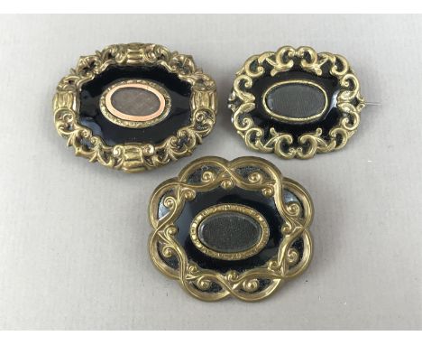 Three Victorian hairwork mourning brooches, each having a central glass locket surrounded by black enamel and scrolling gilt 