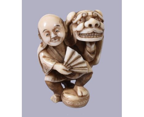 ϒ Homei : A Japanese Ivory Netsuke, depicting a man standing with one foot raised on a drum, he holds a fan in one hand and d