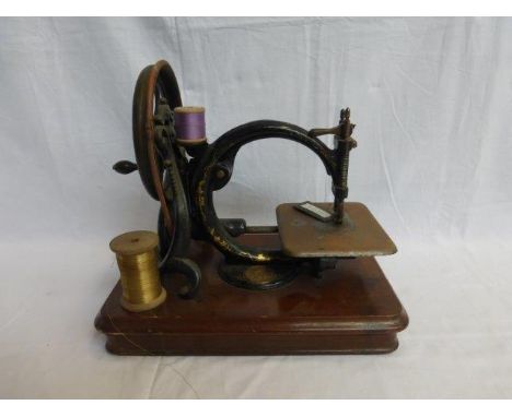 A Willcox & Gibbs sewing machine with medallion attached and lacquered decoration set on an oak base. 