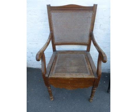 An Edwardian cane seated commode chair.