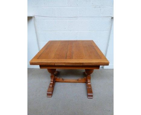 A light oak draw leaf kitchen table raised on turned bulbous supports and a stretcher. 