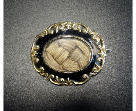 VICTORIAN ENAMEL DECORATED GOLD MOURNING BROOCHthe central glazed panel revealing entwined hair, surrounded by black enamel a