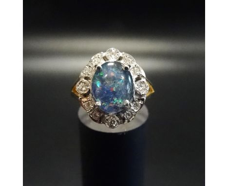 OPAL TRIPLET AND DIAMOND CLUSTER RINGthe central oval opal triplet in twelve diamond surround, on eighteen carat gold shank, 