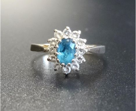 BLUE TOPAZ AND CLEAR GEM SET CLUSTER RINGthe central oval cut blue topaz in clear gem surround, on nine carat gold shank, rin