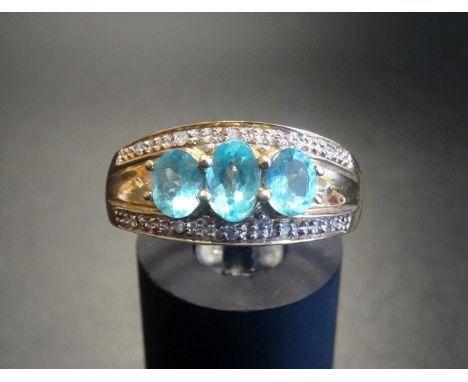 BLUE TOPAZ AND DIAMOND DRESS RINGthe three graduated oval cut topaz gemstones with illusion set diamonds above and below, on 