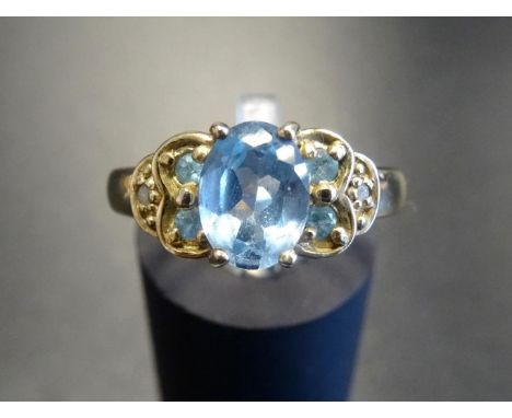 BLUE TOPAZ AND DIAMOND DRESS RINGthe central oval cut topaz flanked by two blue topaz and one diamond to each shoulder, on ni