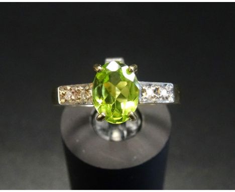 PERIDOT AND DIAMOND RINGthe central oval cut peridot flanked by two diamonds to each shoulder, on eighteen carat gold shank, 