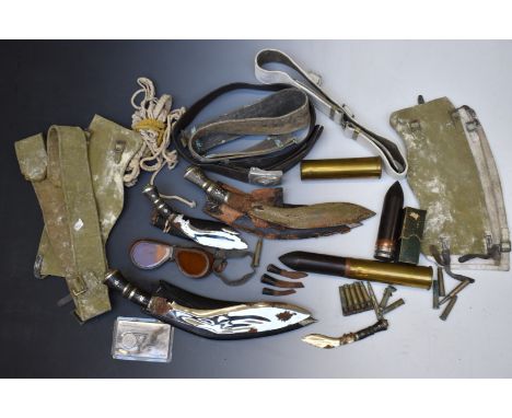 Three Kukri knives, largest blade 30cm, together with two brass shells, military belts and puttees.&nbsp;PLEASE NOTE ALL BLAD