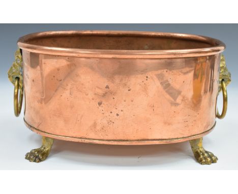 Copper planter with brass lion mask and ring handles, raised on four brass lion paw feet, length 23cm