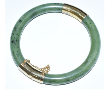 Chinese nephrite jade bangle with yellow metal mounts and safety chain, 7.7cm diameter&nbsp;