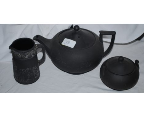 A black porcelain teapot with caddy and milk jug