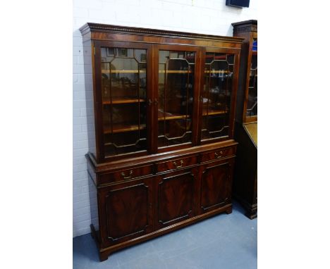 A mahogany bookcase, the cornice top with a dentil frieze over three glazed doors with a shelved interior,  above three short
