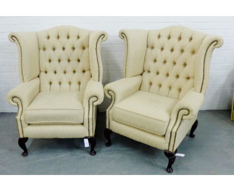 A pair of contemporary cream upholstered button back wing armchairs, raised on cabriole supports, 106 x 90cm 