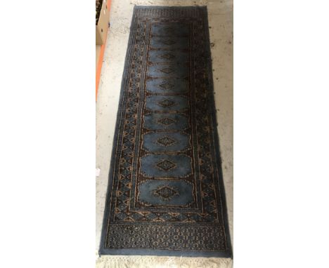 A Bokhara type runner, the central panel set with a row of repeating medallions on a blue and brown ground, within a stepped 