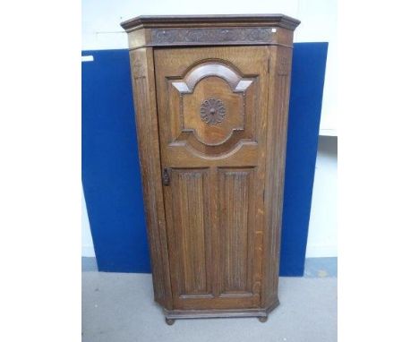 A 1930s oak wardrobe with chamfered, reeded edges and carved decoration to the door front, with internal mirror and shelf, ra